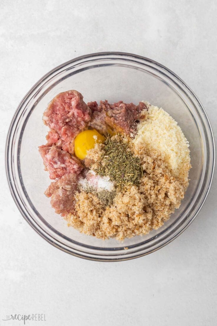 unmixed meatball ingredients in a glass bowl.