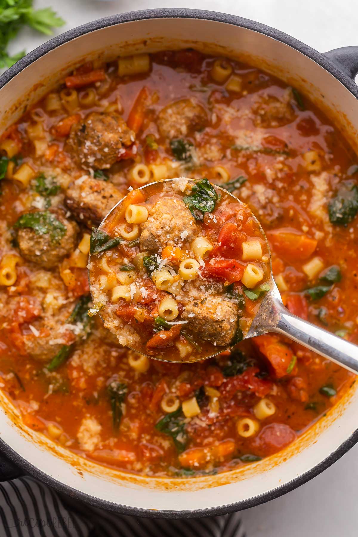 steel ladle scooping meatball soup out of large pot.