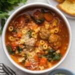 close up overhead shot of a full bowl of meatball soup with grated parmesan cheese on top.