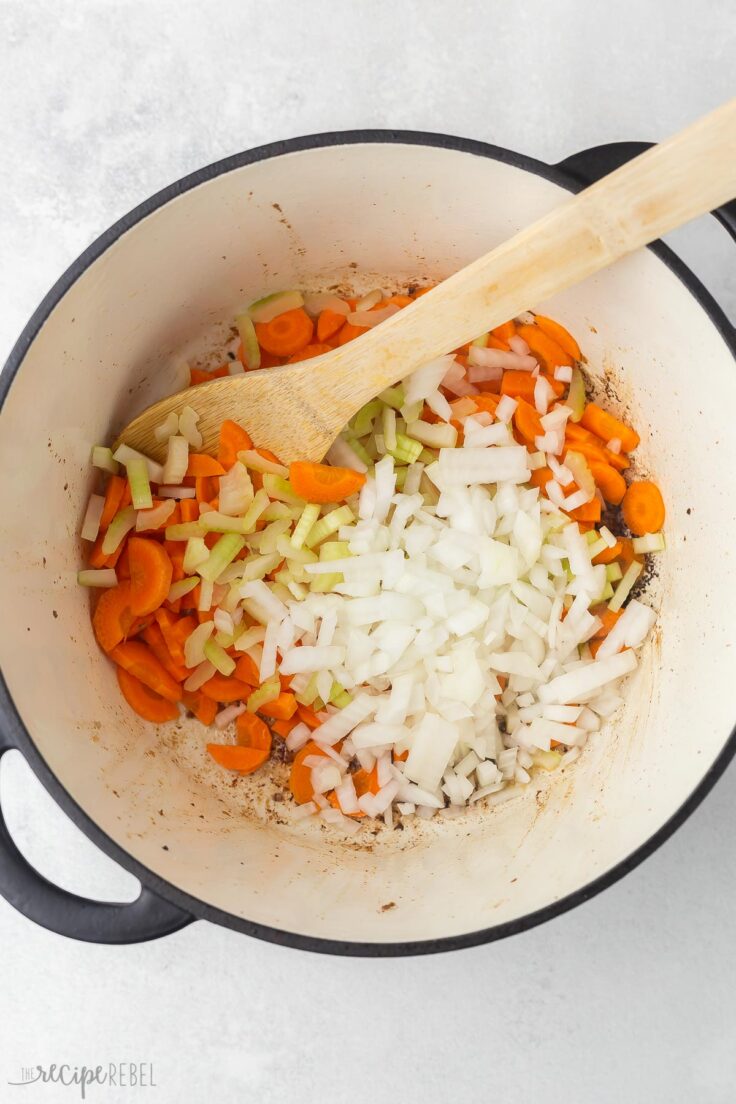 large pot with wooden ladle and chopped vegetables.
