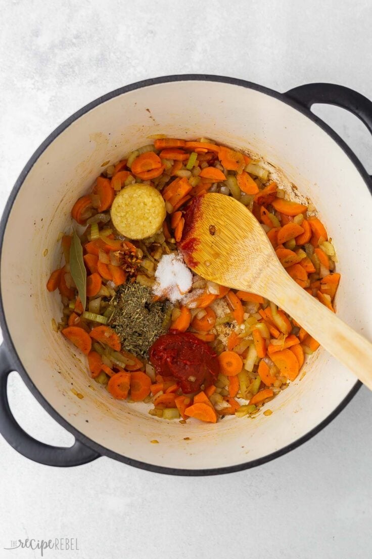 large pot with wooden ladle, sauteed vegetables and spices.