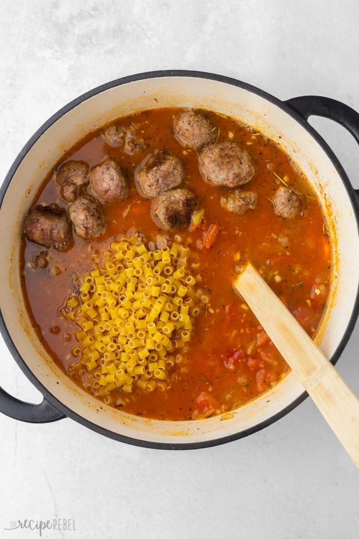 overhead view of pot of soup with meatballs and pasta added on top.