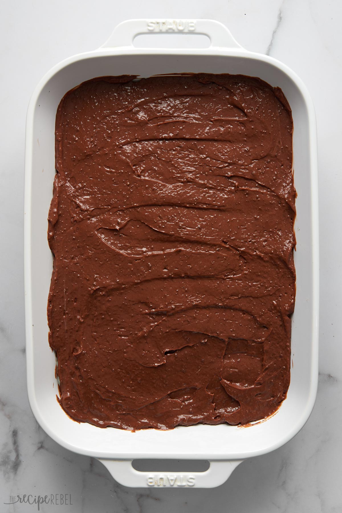 overhead shot of a white pan with chocolate layer spread.