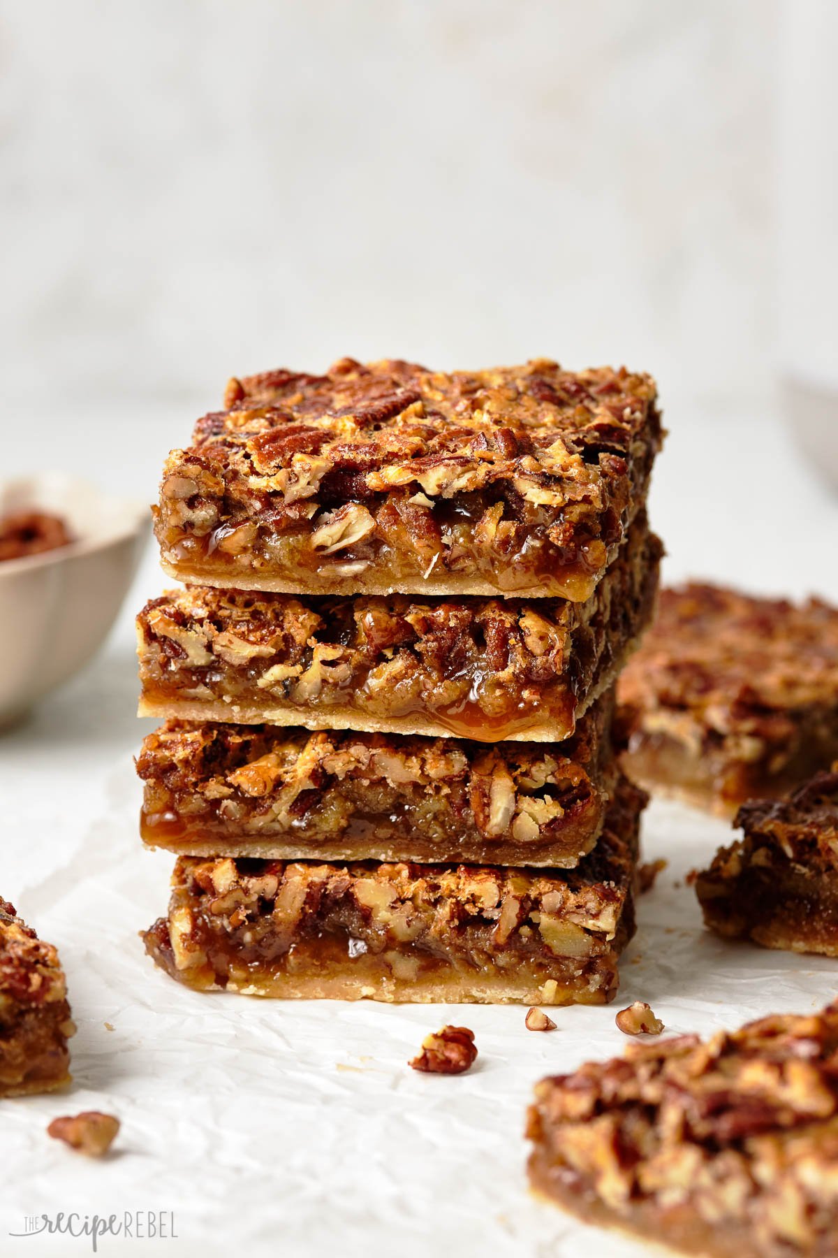 A stack of four pecan pie bars on a white surface. 