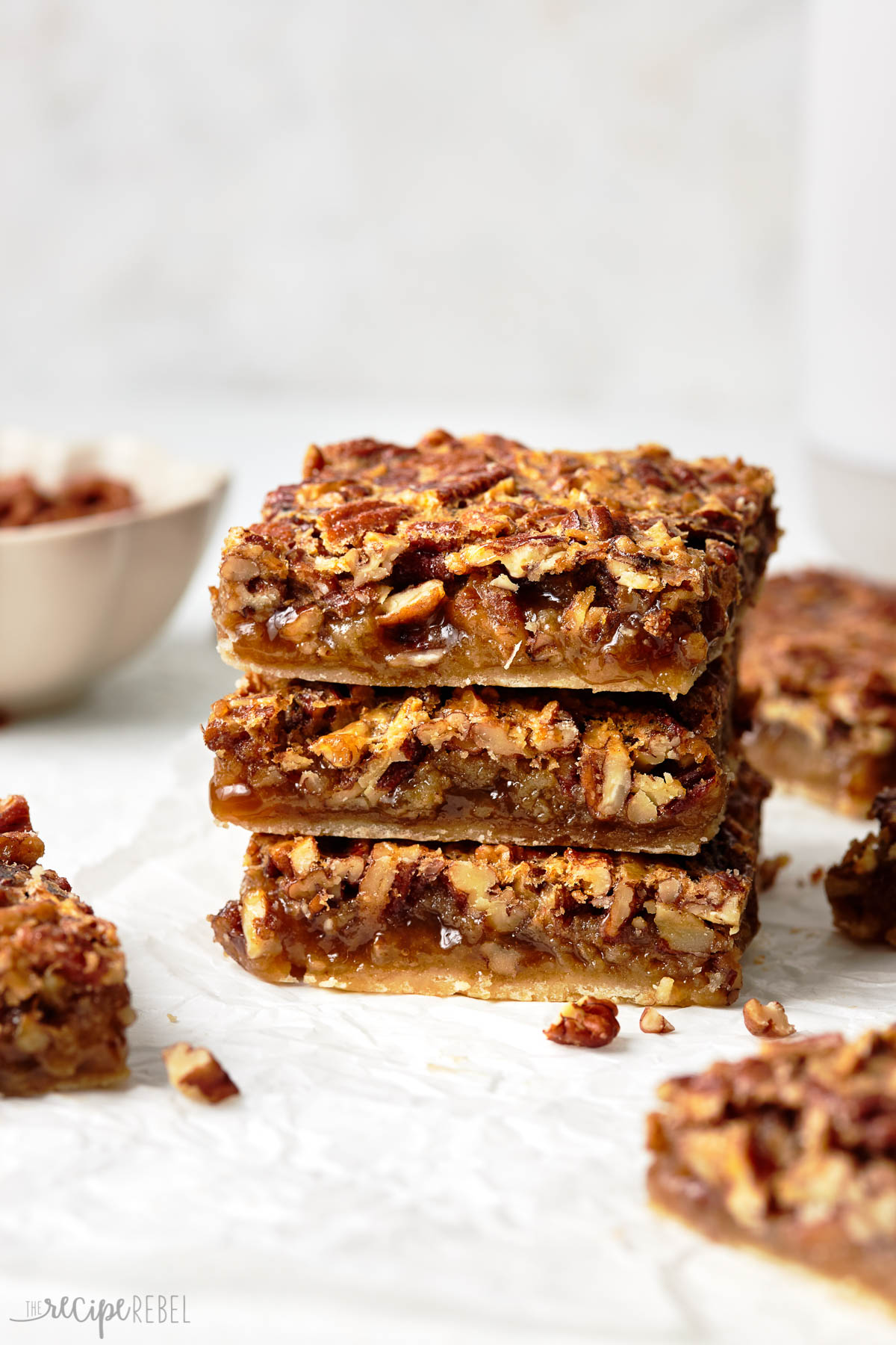 These delicious Pecan Pie Bars are the ultimate fall treat for the holidays! With a thick, buttery shortbread crust and a rich pecan pie filling on top, they are every pecan pie lover's dream! #dessert #baking | pecan recipe | thanksgiving dessert | fall dessert | easy dessert recipe A stack of pecan pie bars.