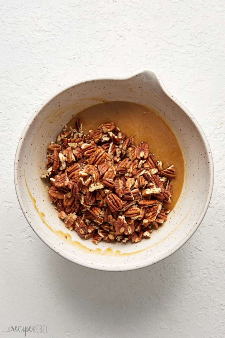 Top view of a white mixing bowl with pecan pie filing mixture in it.