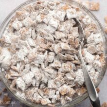 big glass bowl of puppy chow with steel spoon in it.