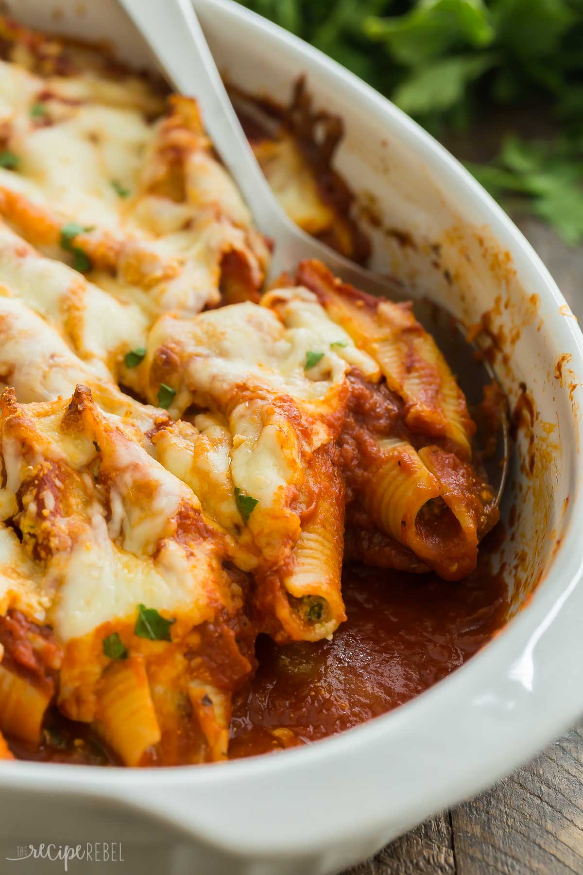close up image of ricotta stuffed shells with spoon scooping.