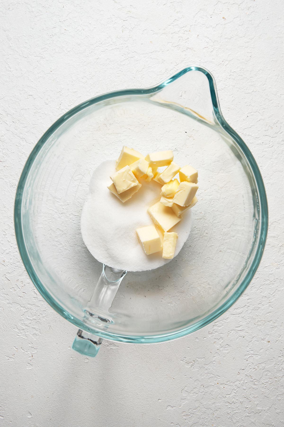 Top view of glass mixing bowl with butter and sugar in it.