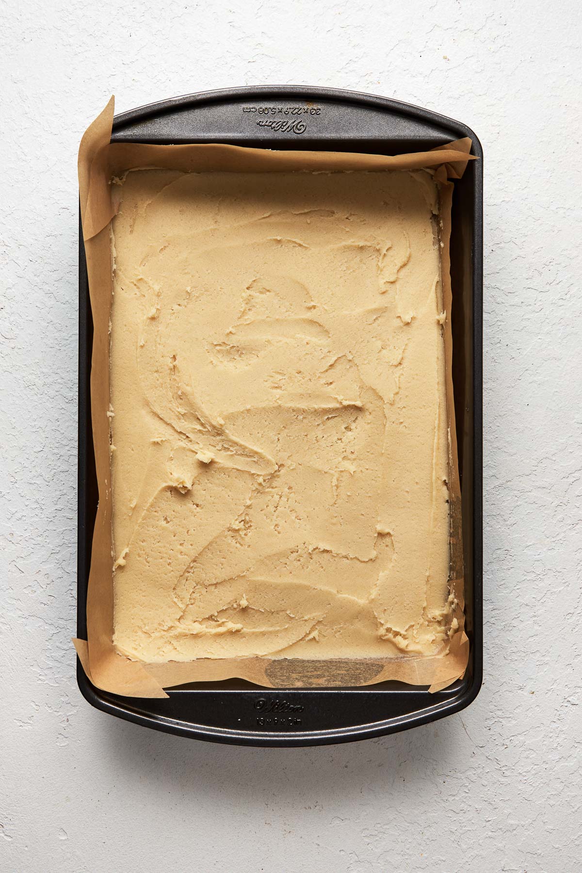 Top view of a baking pan with cookie bar dough in the bottom.