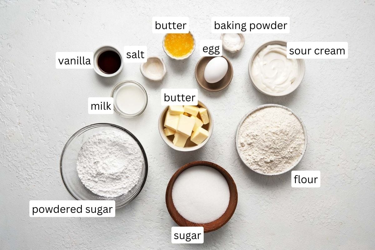 Top view of ingredients needed to make Sugar Cookie Bars in small bowls on a white surface.
