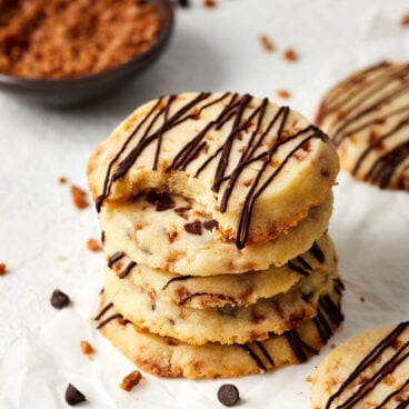 stack of cookies on parchment paper with toffee bits around.