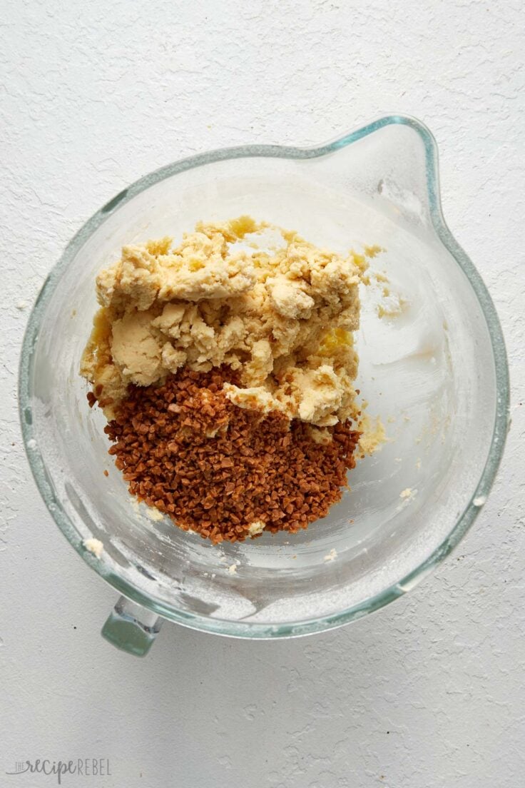 mixed ingredients in glass mixing bowl with toffee bits added on top.