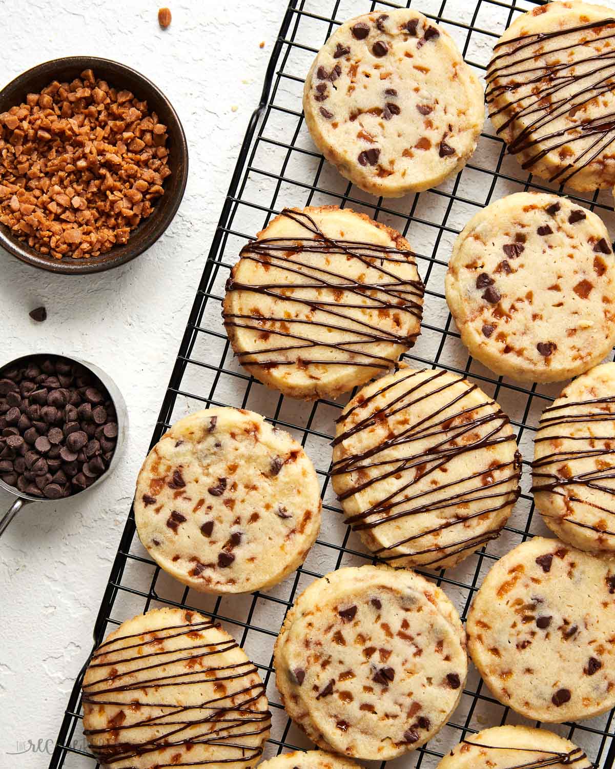 toffee shortbread cookies with drizzled chocolate on a cooling rack.
