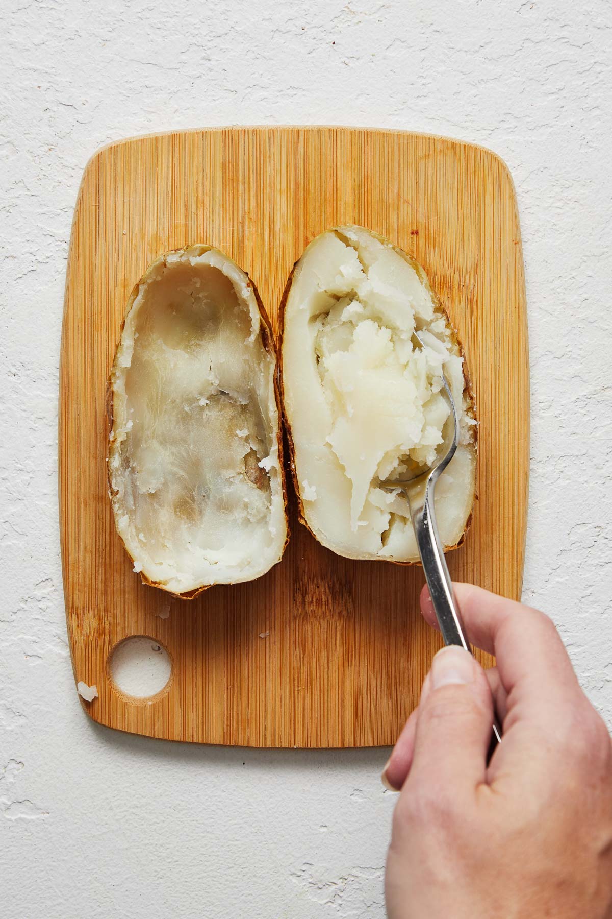 Top view of a baked potato chopped in half with the potato being scooped out.