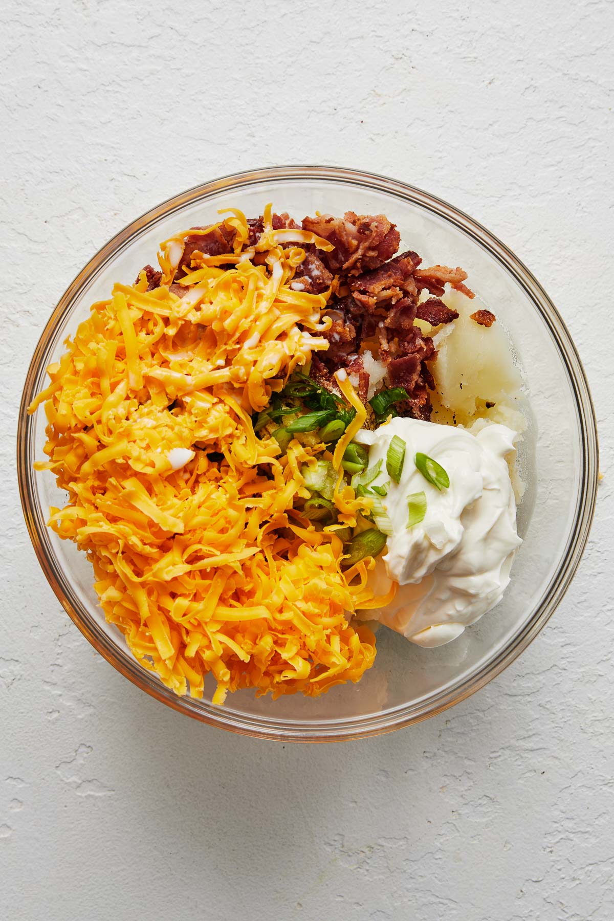 Top view of a glass mixing bowl with fillings in it, unmixed.