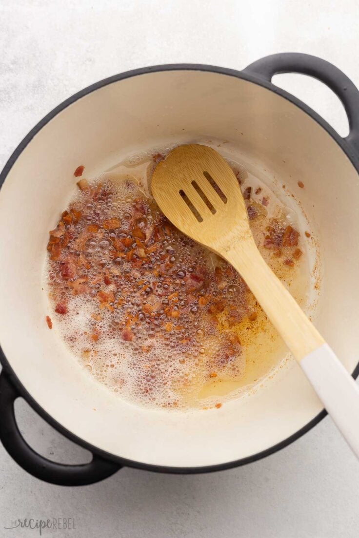 large pot with cooked chopped bacon and wooden ladle inside.