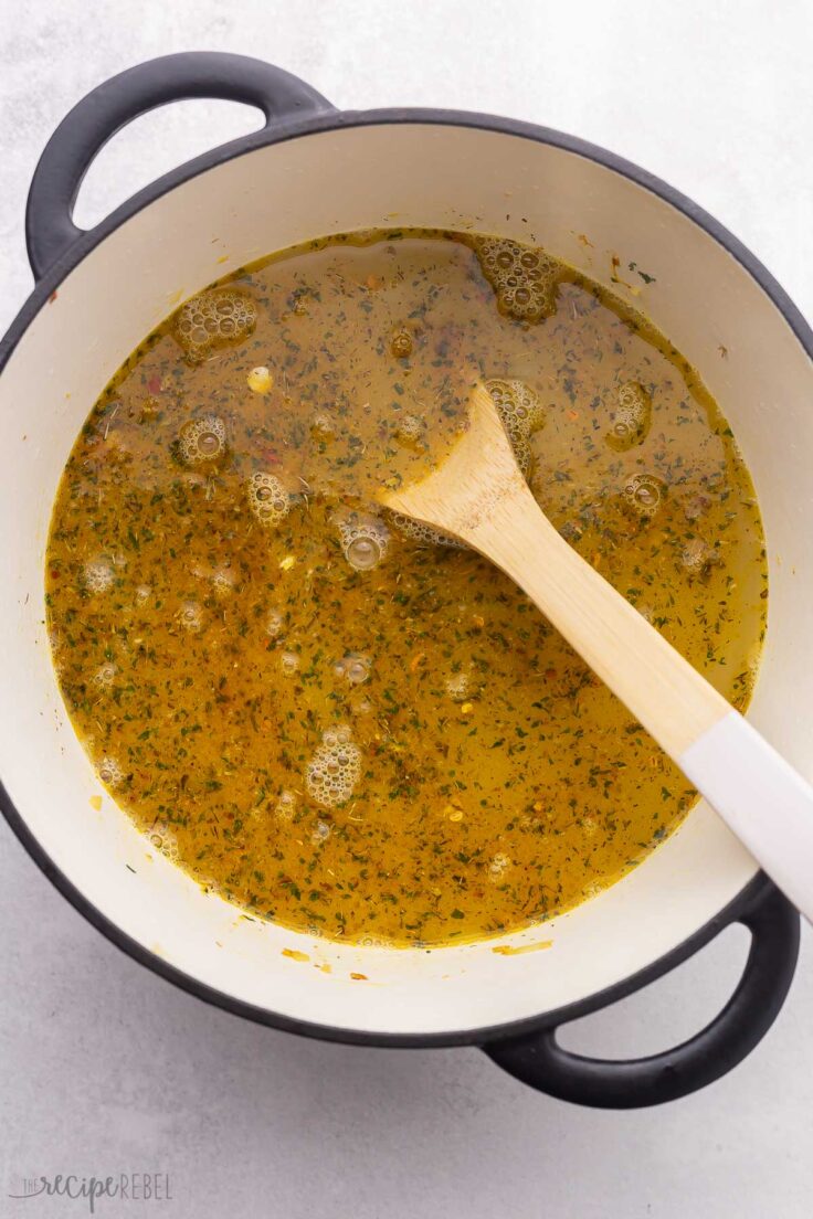 overhead view of large pot with broth and wooden ladle.