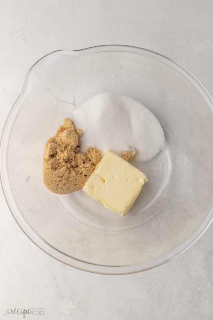 glass mixing bowl with sugar, butter, and brown sugar in it.