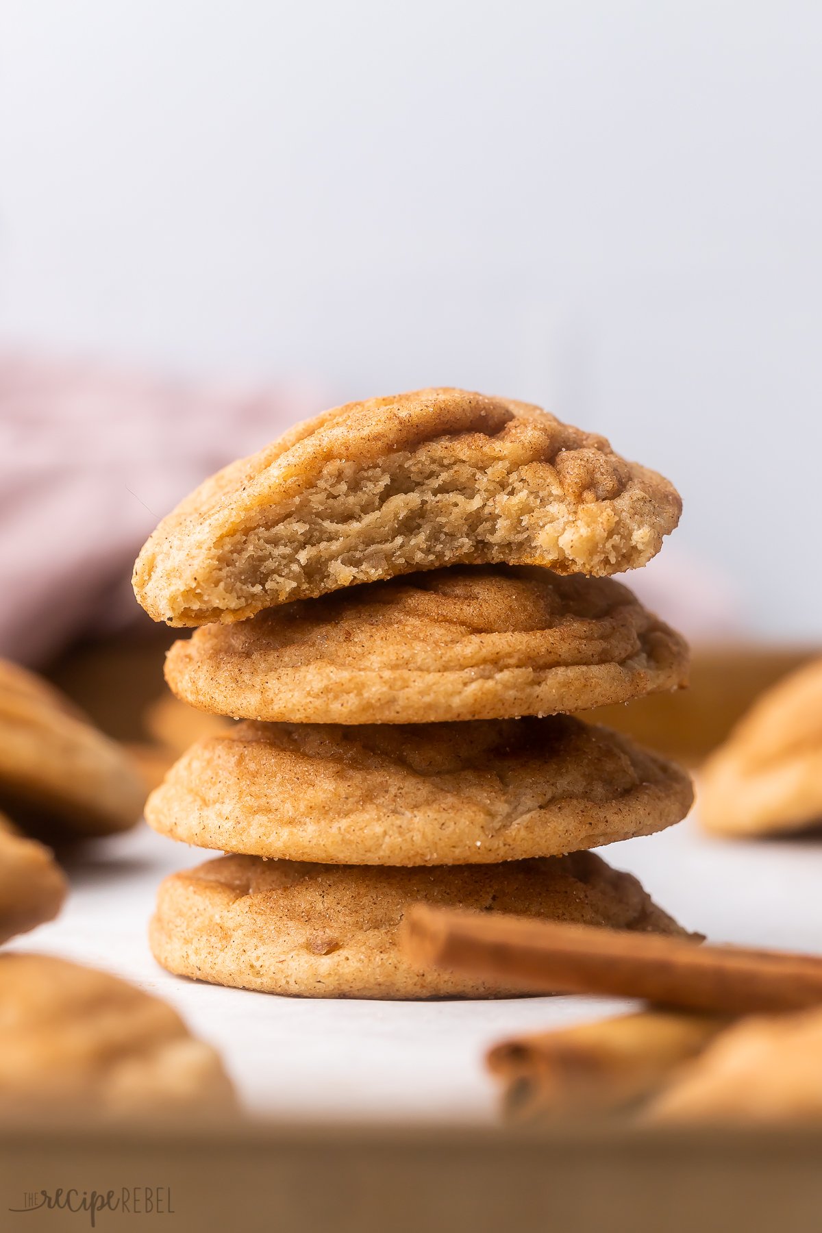 This easy Chai Cookies Recipe are soft and chewy, made with a homemade chai spice blend and coated with cinnamon sugar. They'll quickly become a new favorite fall cookie recipe! #cookie #christmas #baking | baking recipe | cookie recipe | christmas cookies | fall baking | fall cookies | christmas baking | snickerdoodles | cookie recipes stack of chai cookies with bite out of top cookie on white surface.