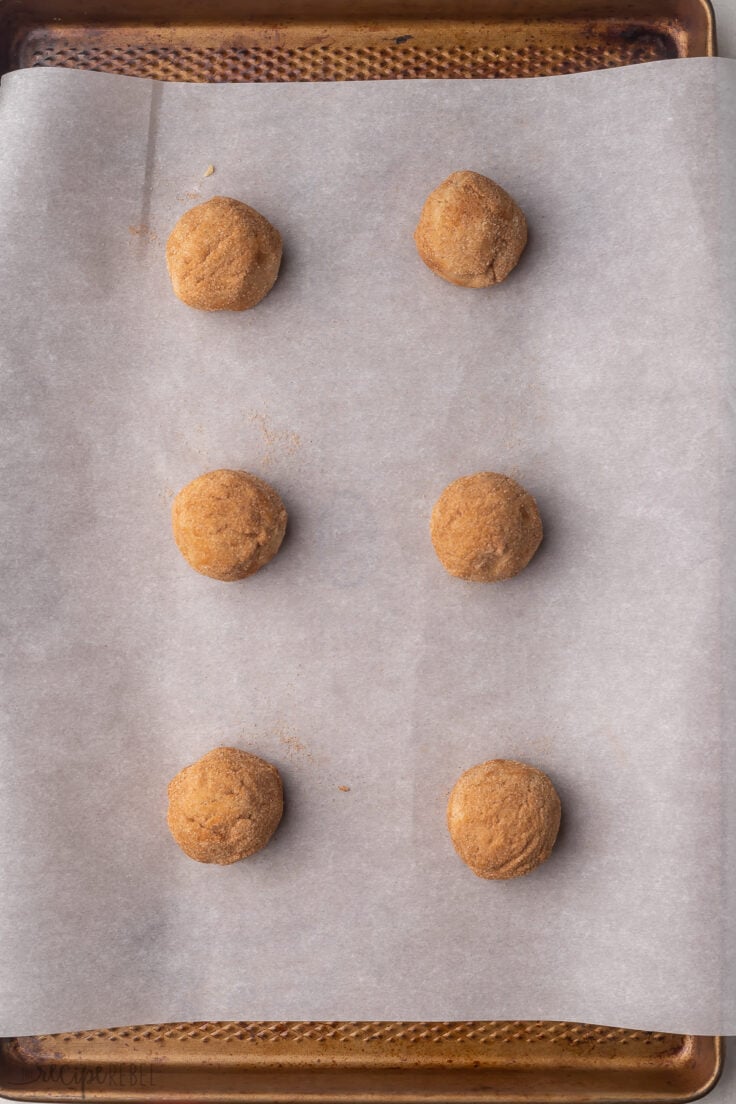 six cookies on sheet pan lined with parchment paper ready to be baked.