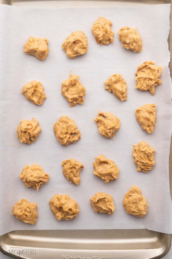 Top view of peanut butter balls on parchment paper on a baking tray.