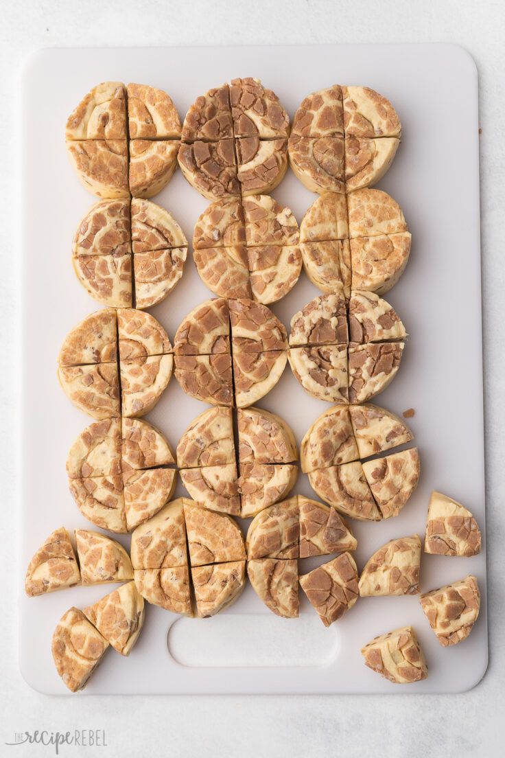 Top view of cinnamon rolls being cut into 4 pieces on a chopping board.