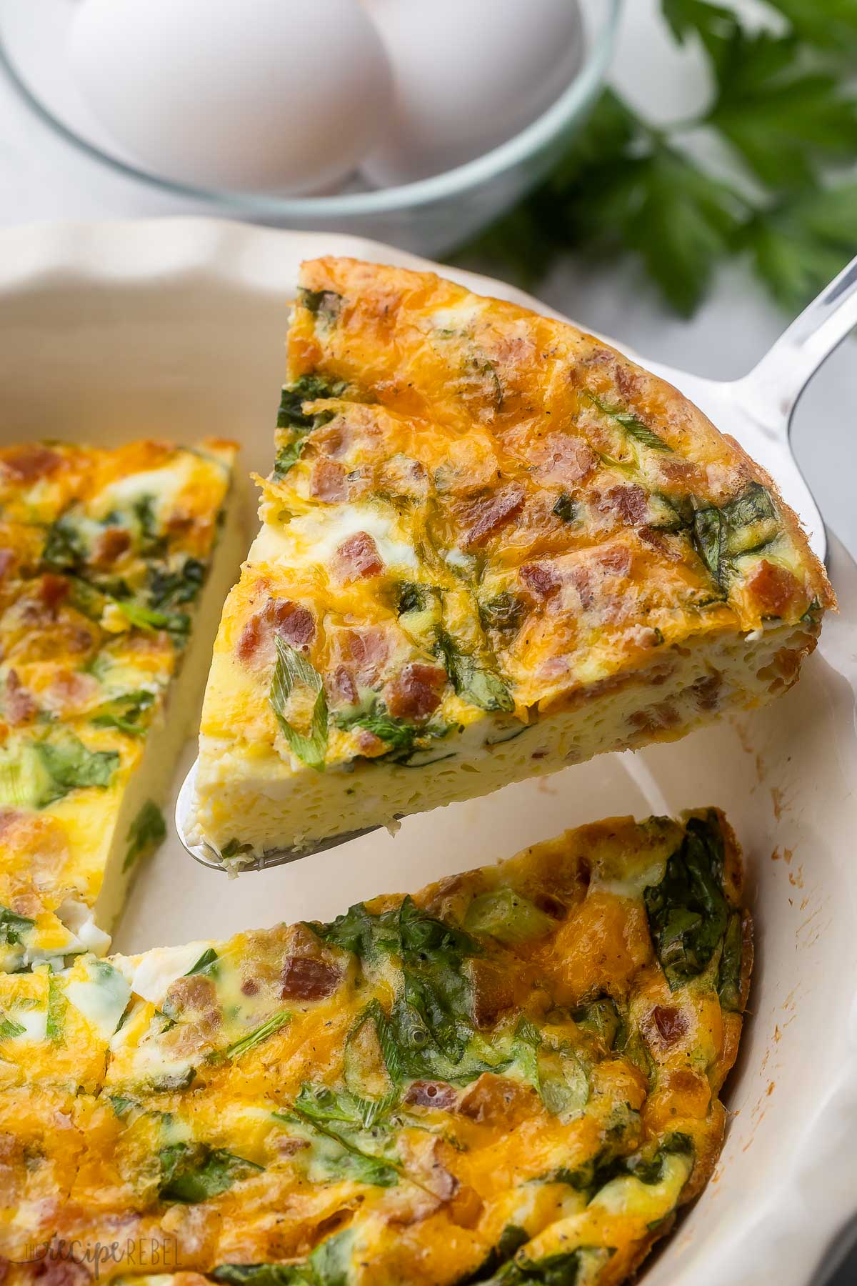 Close up view of a slice of Crustless Quiche being lifted from the dish.
