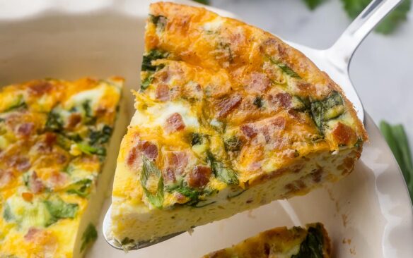 Close up view of a slice of Crustless Quiche being lifted from the dish.