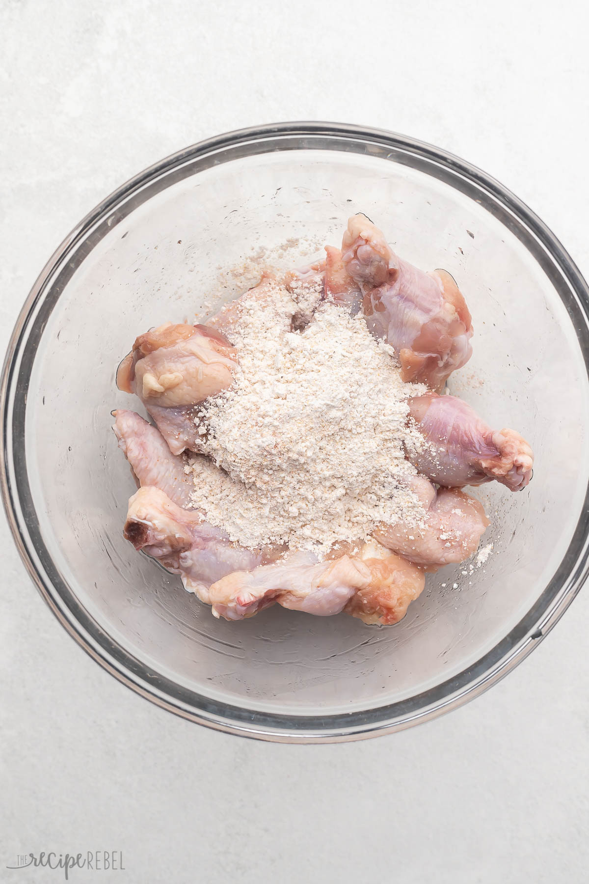 Corn starch, Parmesan, seasoning salt, garlic powder, paprika and pepper being added to the wings, which will be tossed to coat them.