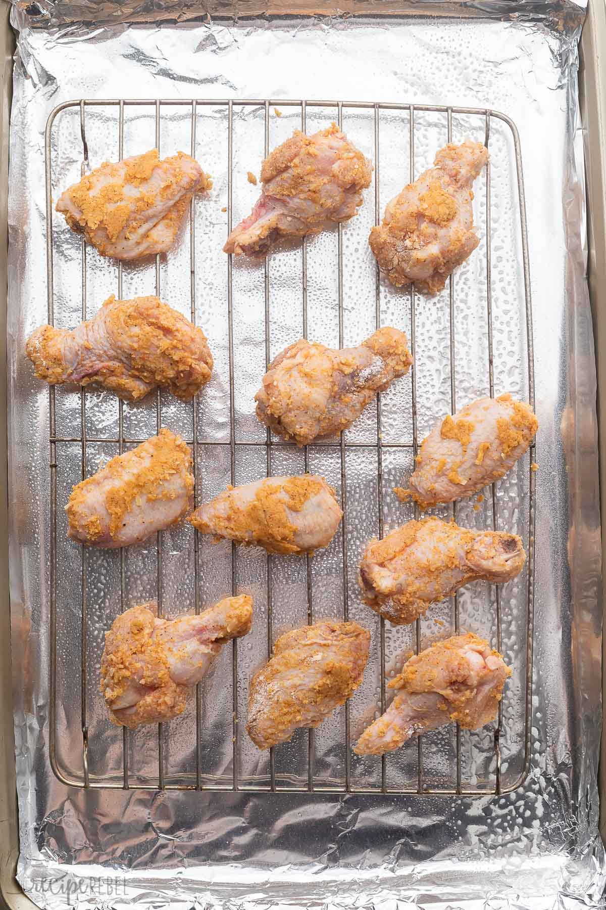 Uncooked Garlic Parmesan Chicken Wings on a wire rack over tin foil.