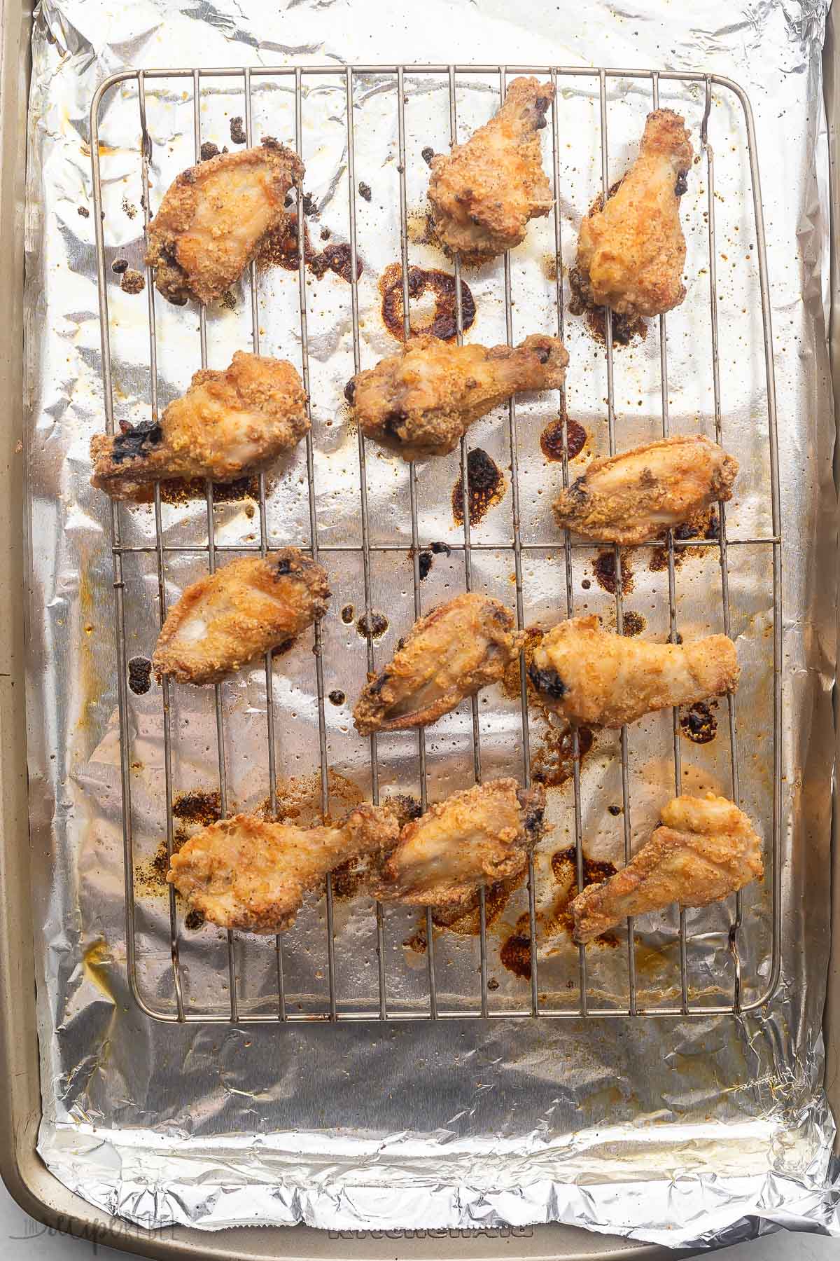 Freshly baked Garlic Parmesan Chicken Wings on a wire rack over tin foil.