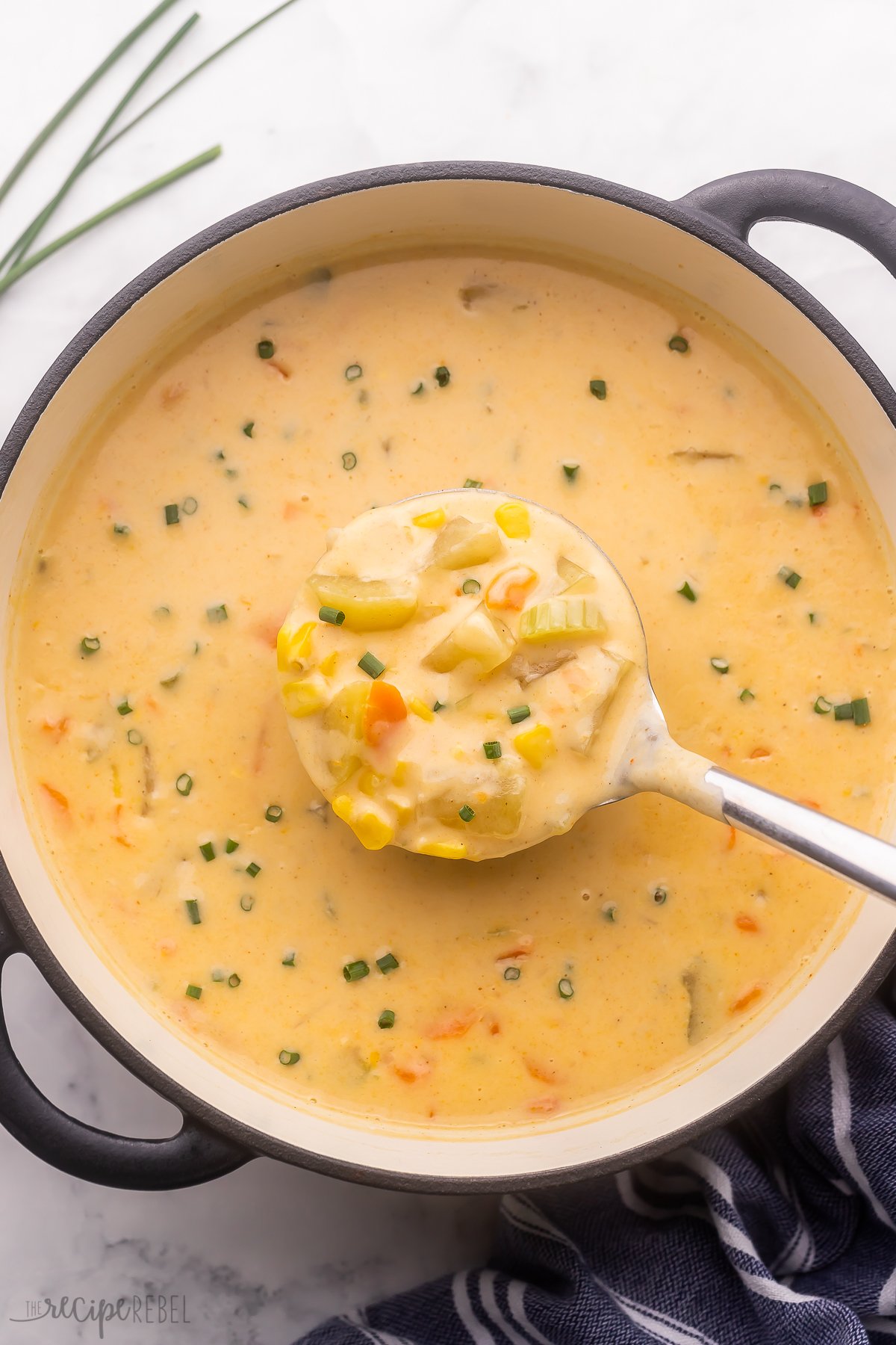 overhead shot of metal ladle scooping nacho potato soup out of pot.