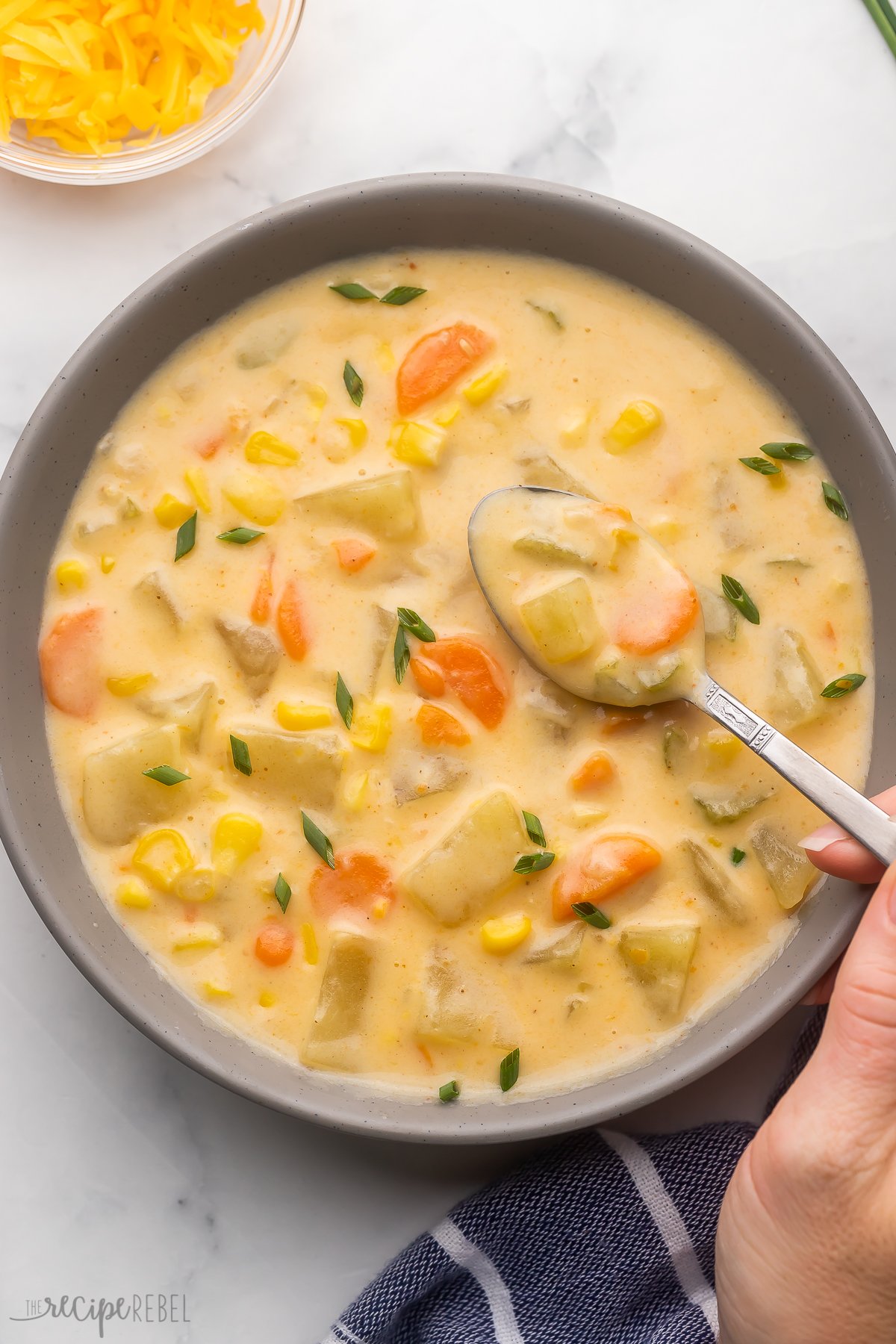 grey bowl filled with nacho potato soup and spoon scooping out.