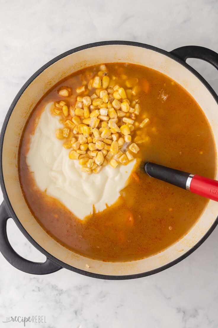 large pot of soup with sauce and corn added.