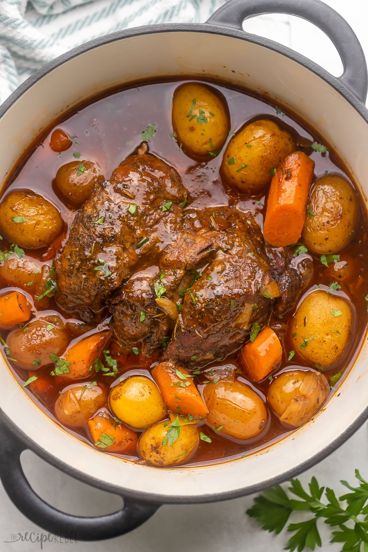 This easy oven Pot Roast recipe makes a truly delicious dinner centerpiece, perfect for the whole family for Sunday dinners or special occasions! With juicy beef seasoned in a homemade spice rub, it's cooked with potatoes and carrots until tender in a flavorful gravy made from scratch - it's the perfect pot roast! #dinner #recipe | pot roast recipe | beef roast | chuck roast | dinner ideas | dinner recipes | chuck roast recipes | sunday dinner | holiday dinner recipes Top view of Pot Roast in a Dutch Oven.