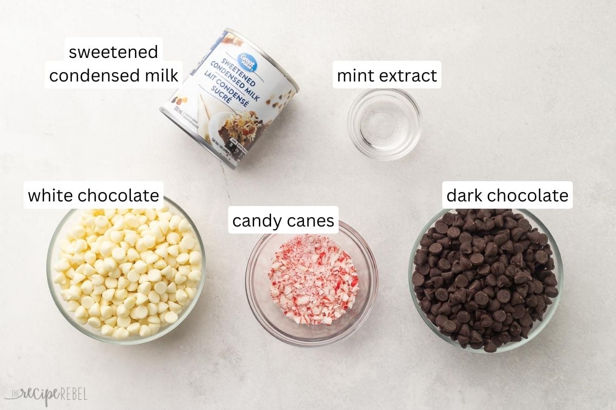 Top view of ingredients needed to make Peppermint Bark Fudge in small bowls on a white surface.