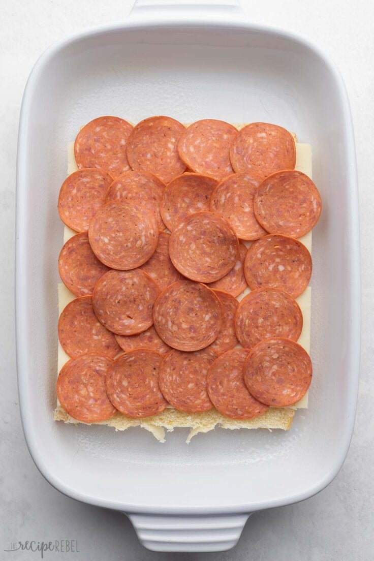 A layer of pepperoni on the slider rolls.