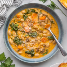 square image of tuscan bean soup in a blue bowl.