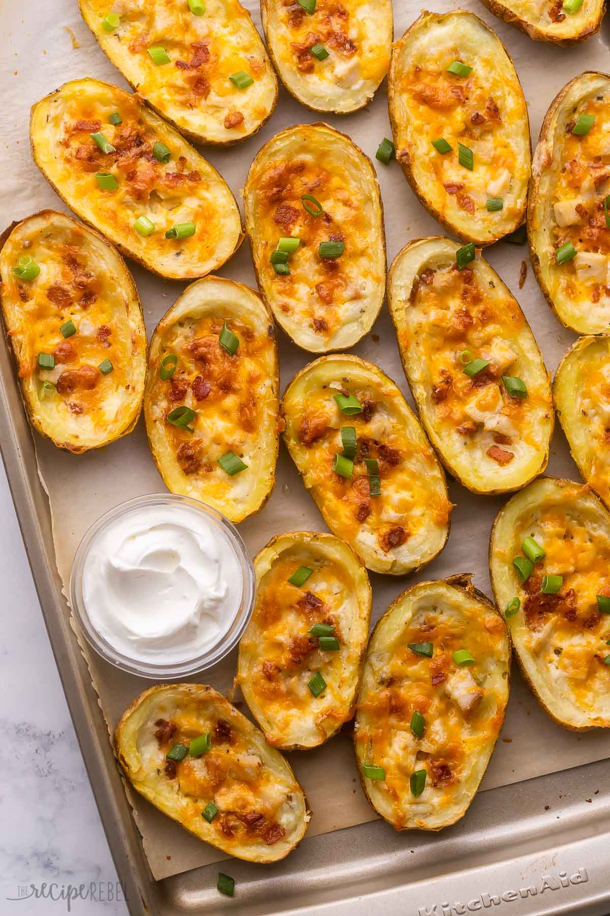 baked potato skins on a pan with a bowl of sour cream.
