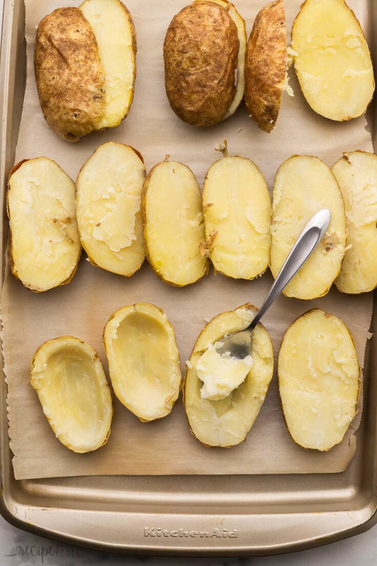 halved cooked potatoes on sheet pan with spoon.
