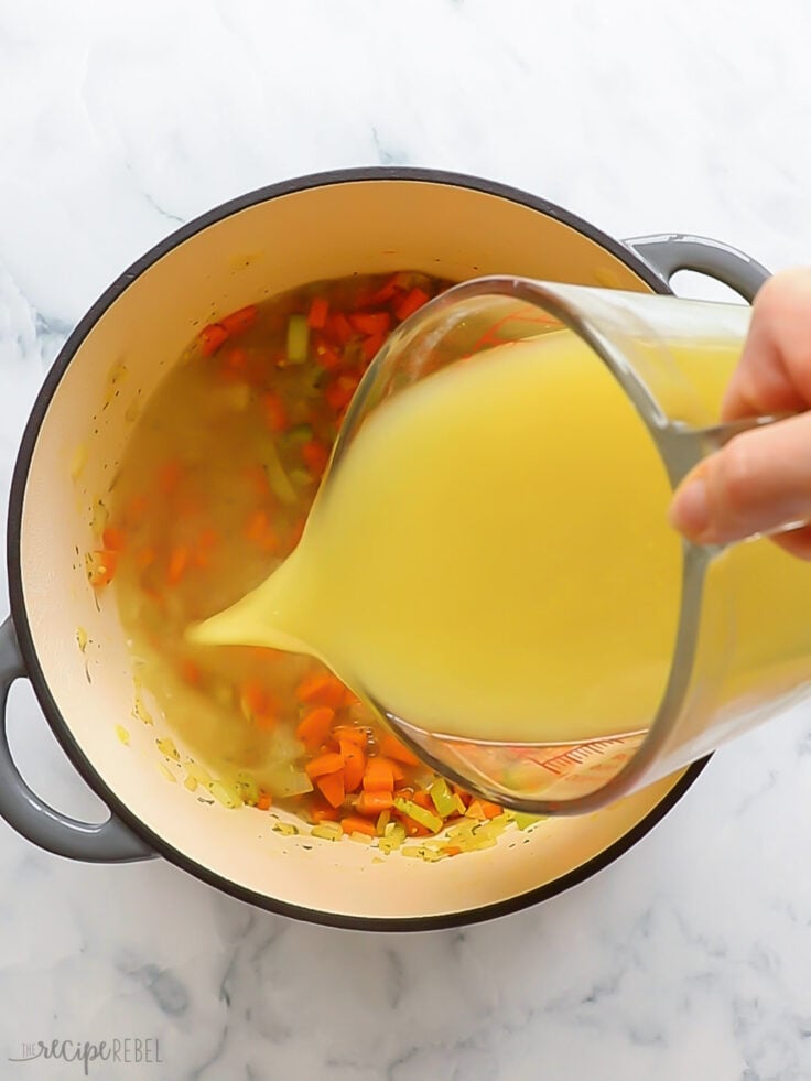 Broth added to vegetables in pot.