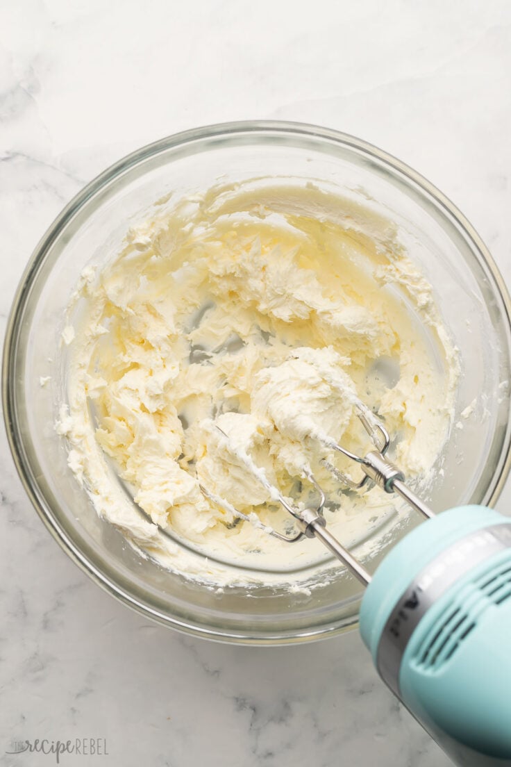 glass bowl with mixed cream cheese and mixer off to the side.