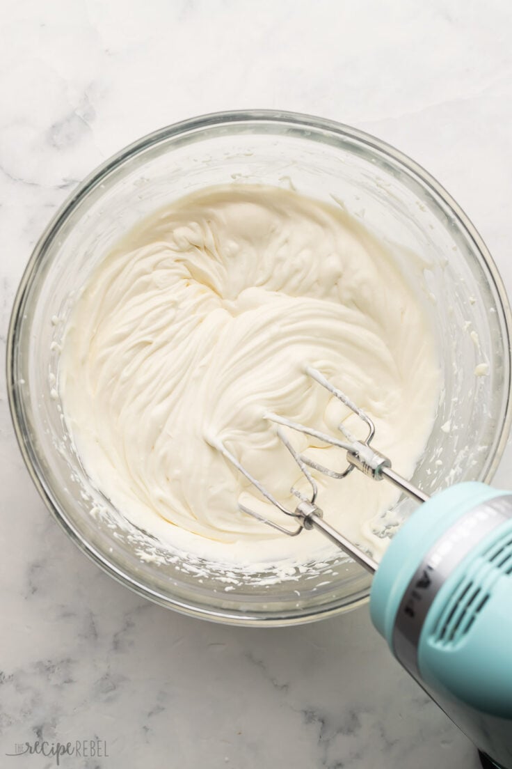 cream cheese fruit dip completely mixed in glass bowl with mixer beside.