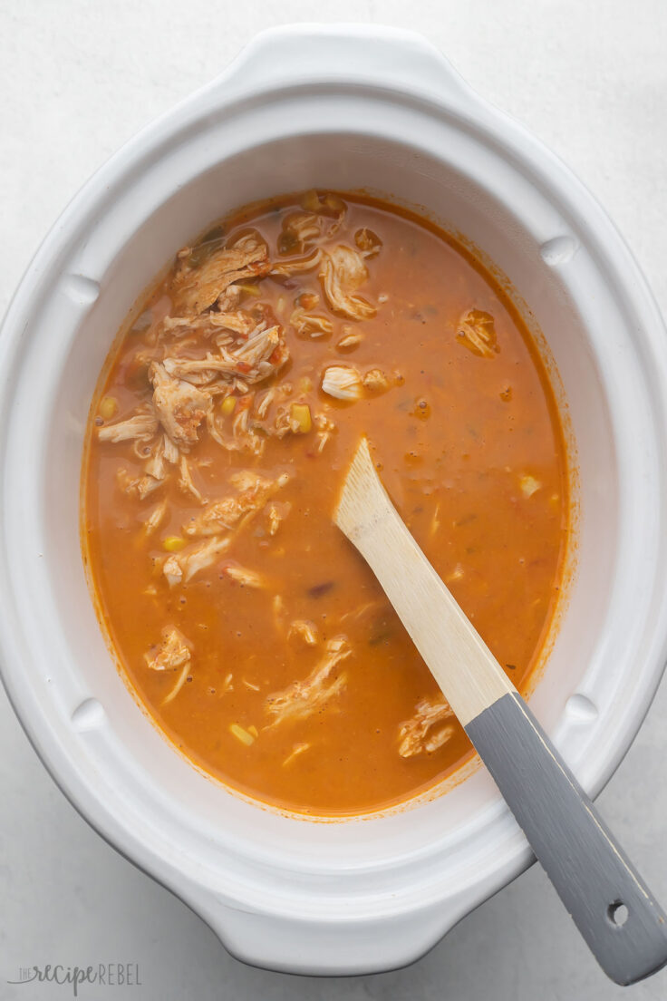 white slow cooker with shredded chicken added back into soup.