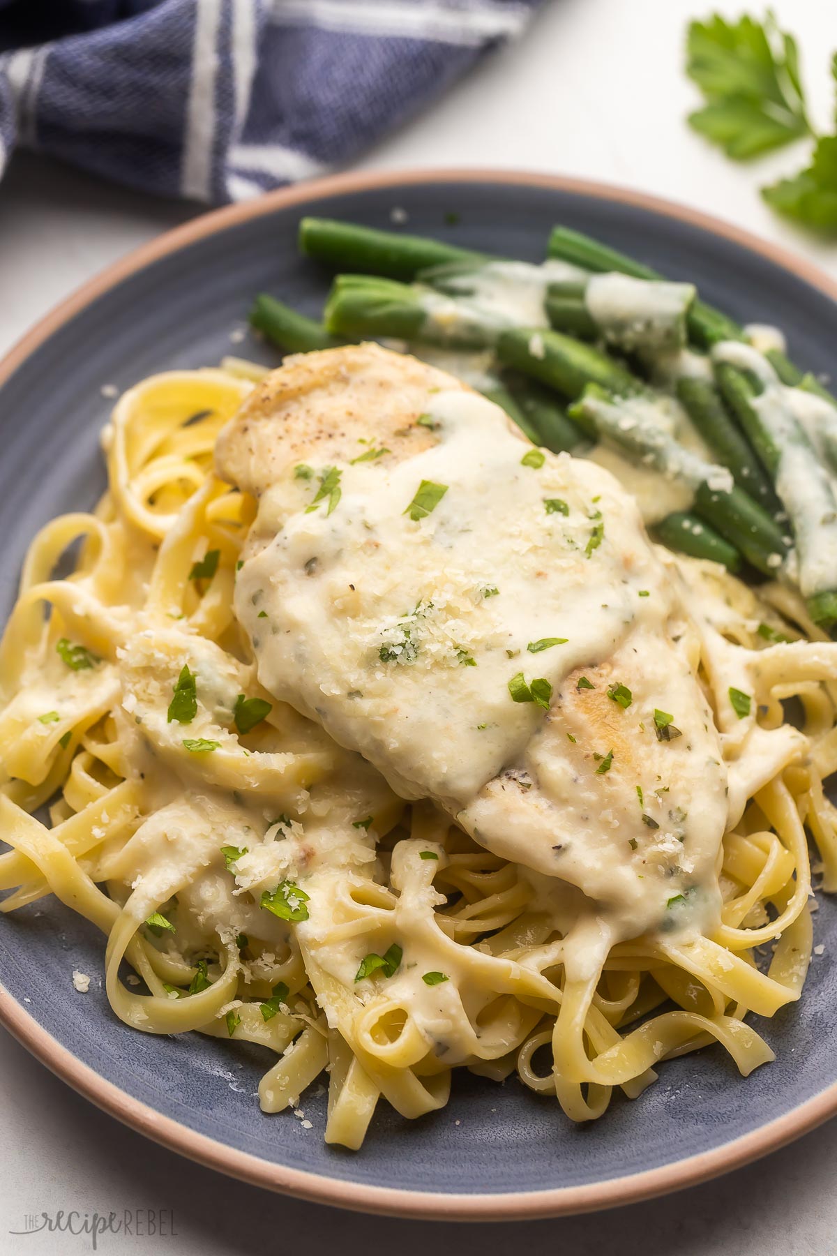 creamy garlic chicken breast on top of pasta with a side of green beans.