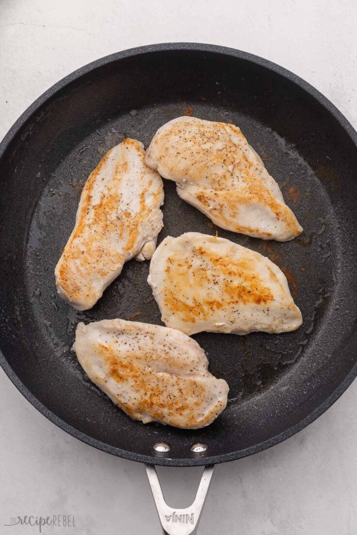 Chicken breasts seared in black skillet.