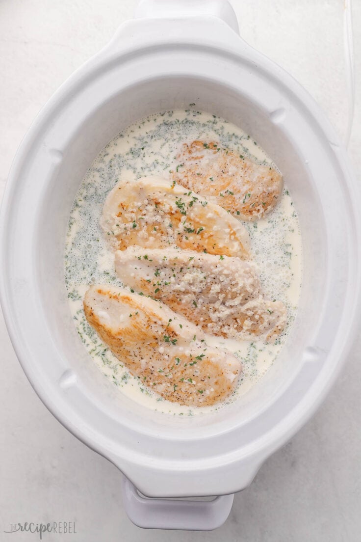 Seared chicken breasts in crockpot with creamy garlic sauce.