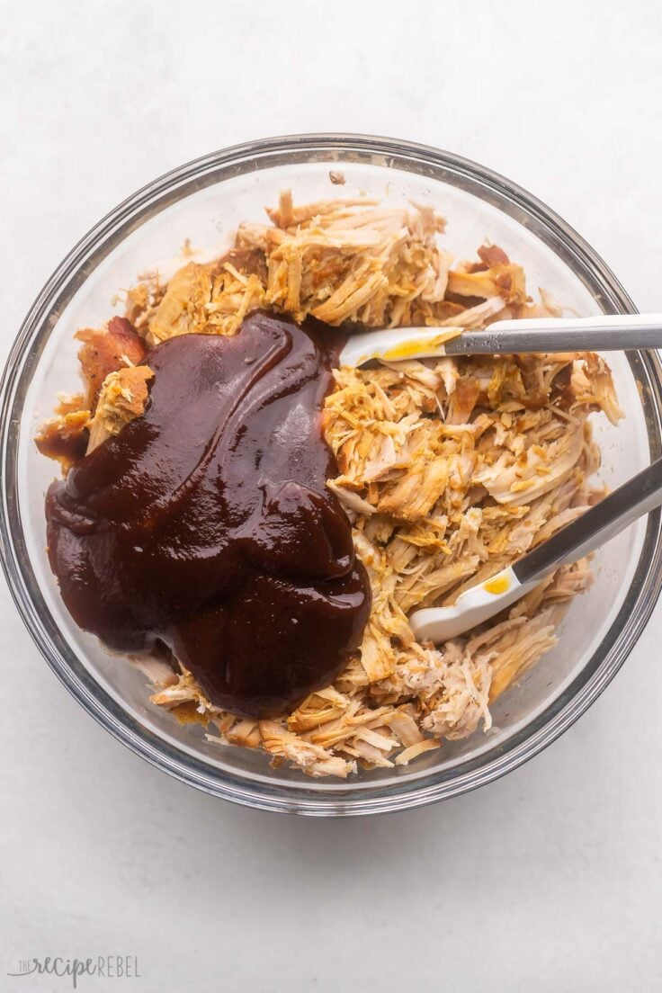 glass bowl filled with pulled pork and bbq sauce added on top.