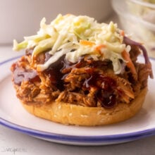 close up of bun topped with pulled pork, bbq sauce, and coleslaw.